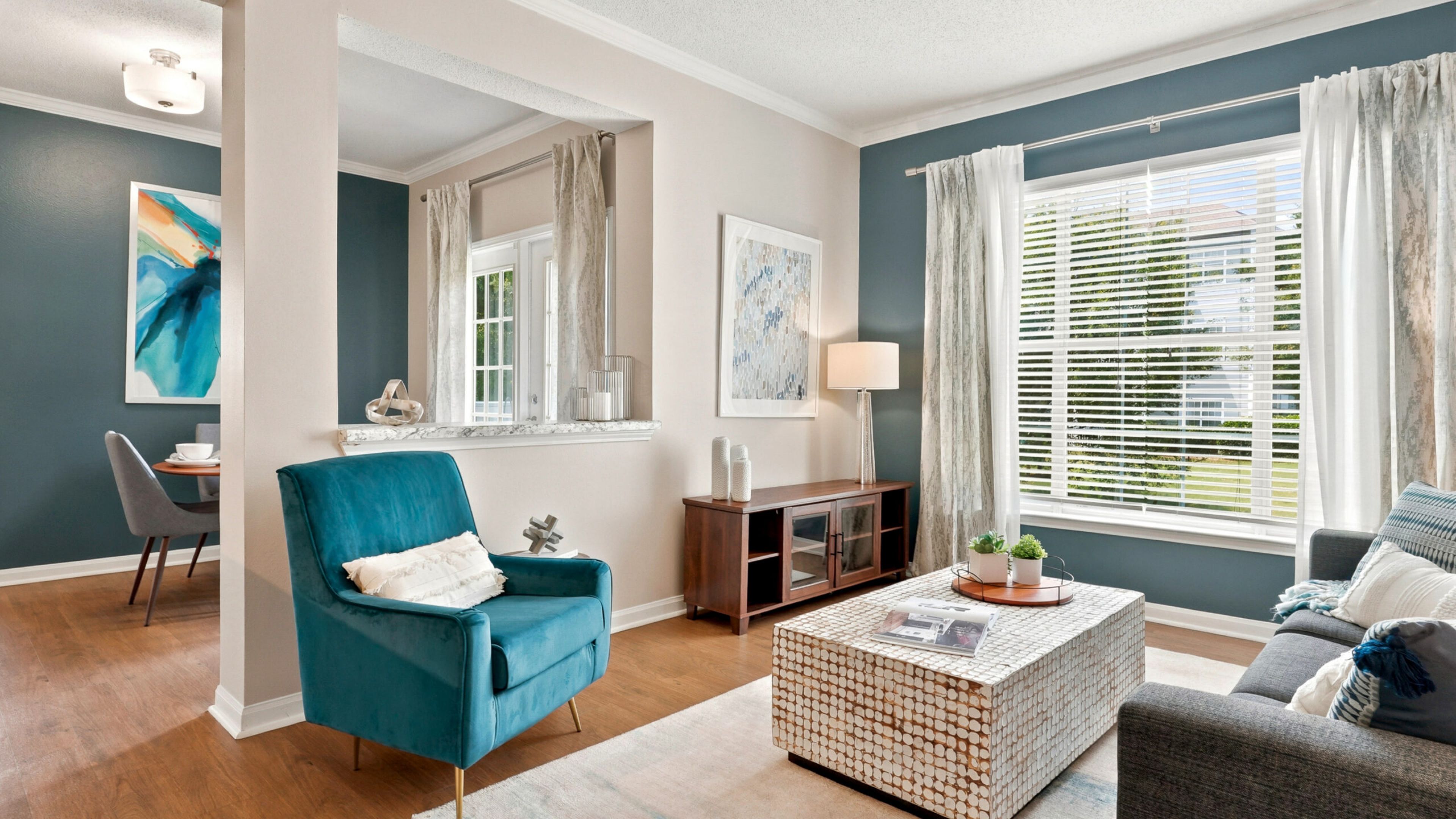 Hawthorne at Lake Heather beautifully decorated living room featuring a cozy seating area with a blue armchair, a stylish coffee table, and large windows letting in plenty of natural light.