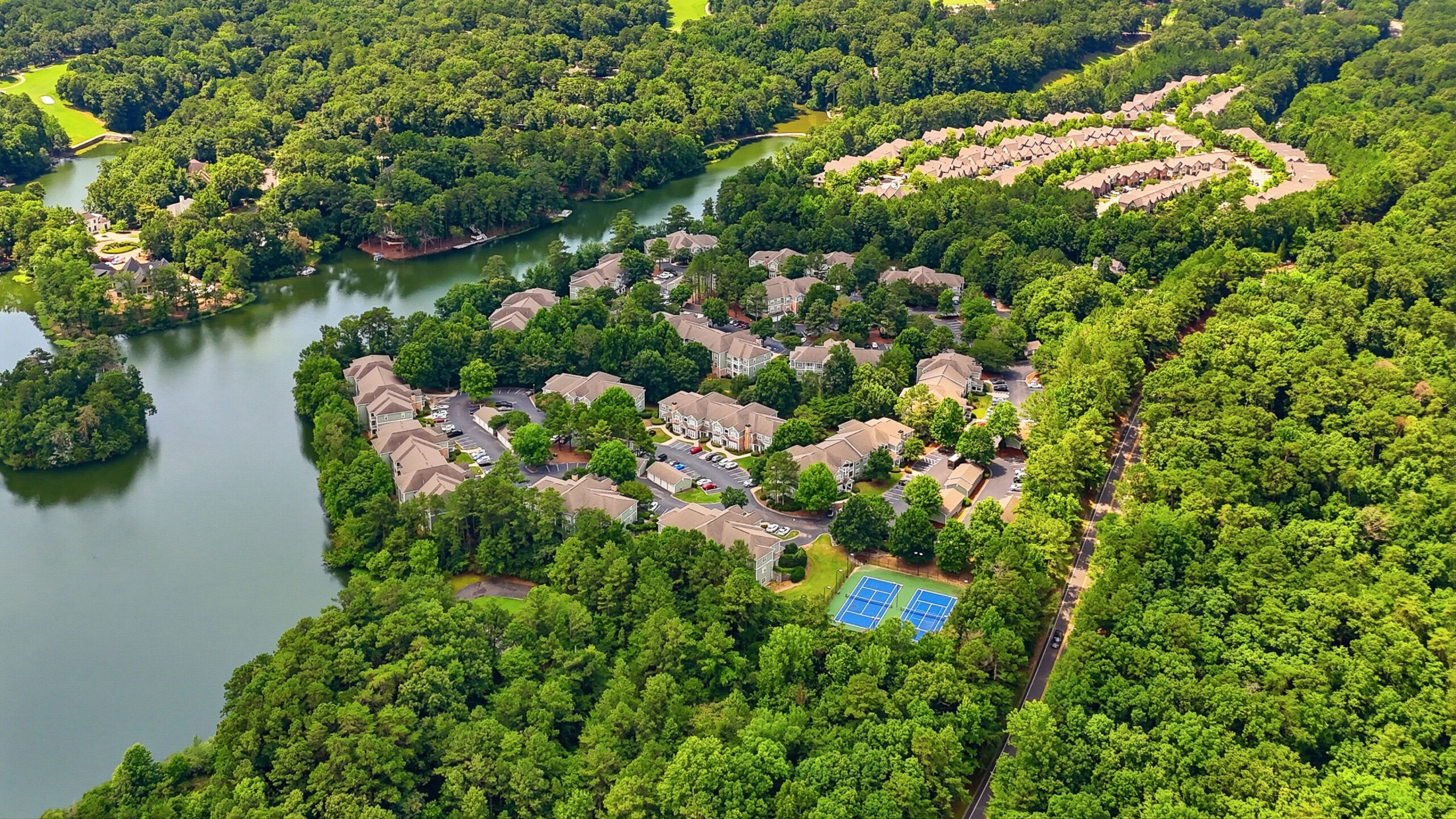 Hawthorne at Lake Heather exterior showcasing its well-maintained buildings surrounded by lush trees and landscaping, with a clear blue sky overhead.
