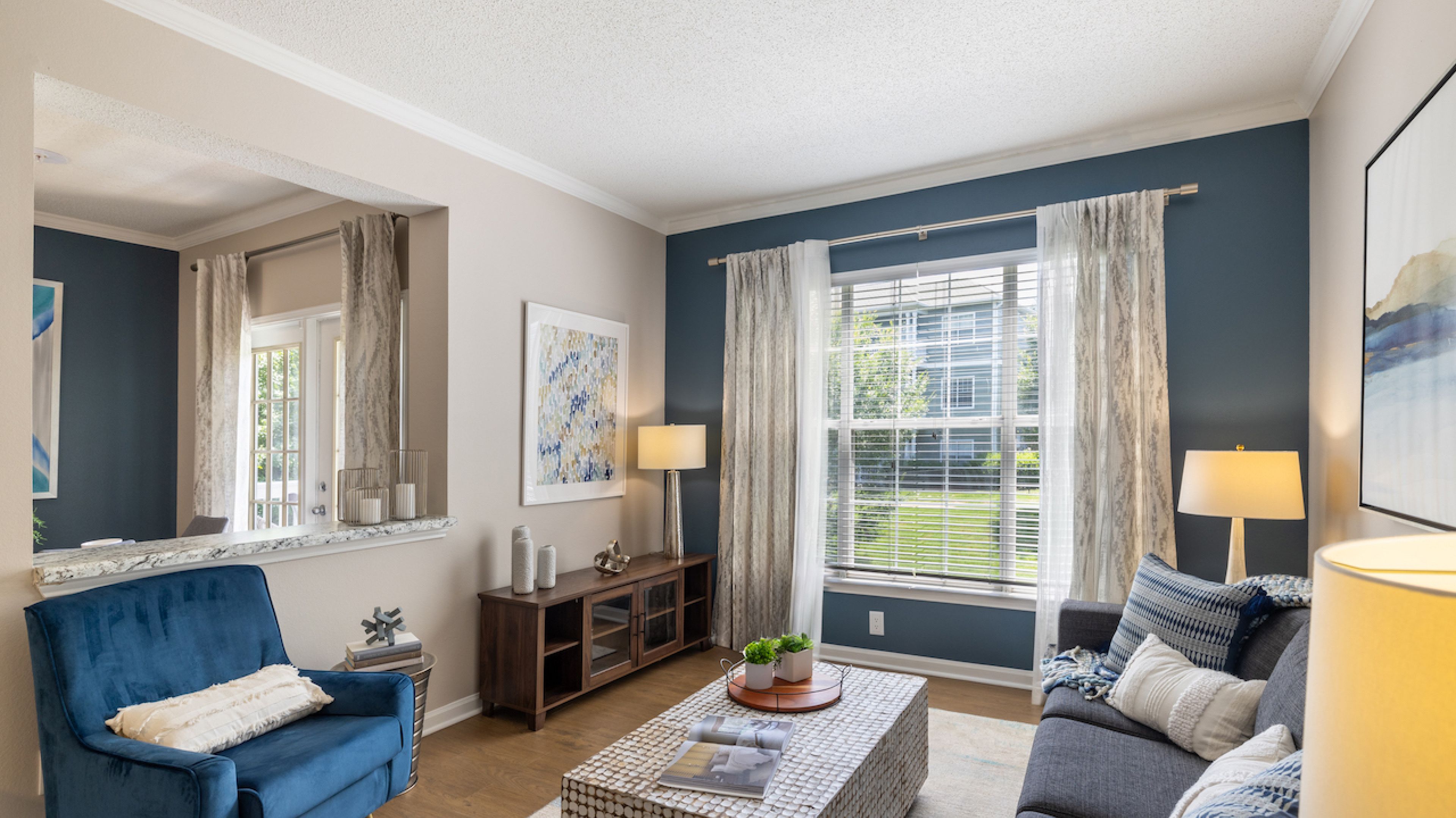 Hawthorne at Lake Heather beautifully decorated living room featuring a cozy seating area with a blue armchair, a stylish coffee table, and large windows letting in plenty of natural light.